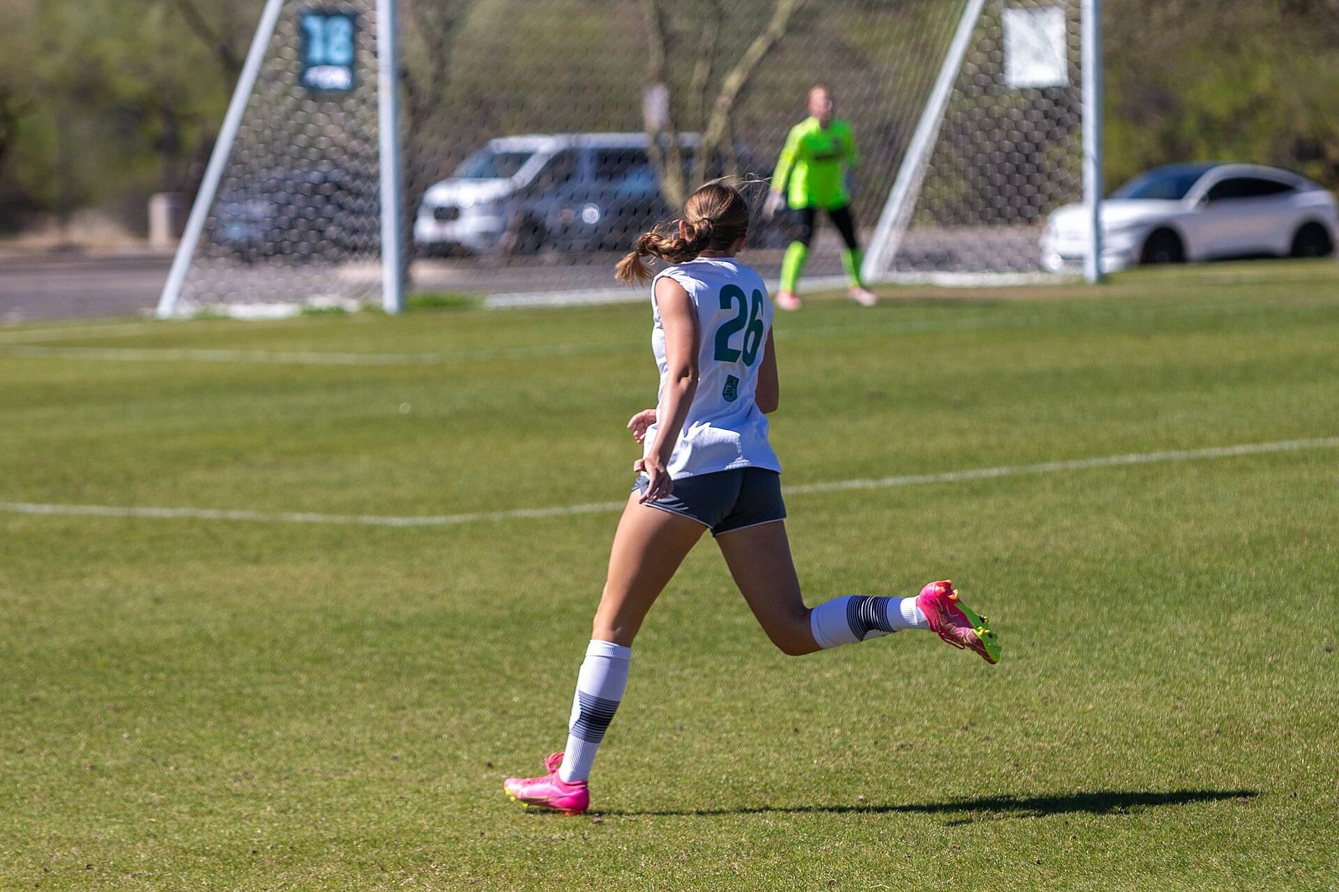 A youth player, jersey 26, heads up the pitch